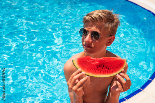 teenager by the blue pool with a slice of ripe watermelon