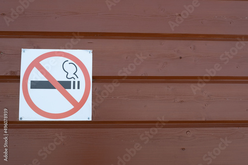 A sign banning smoking on a wooden wall. Warning about the dangers of smoking.