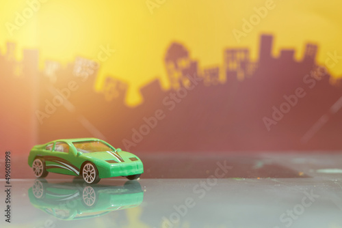 Fototapeta Naklejka Na Ścianę i Meble -  Green saloon car toy selective focus on blur city background