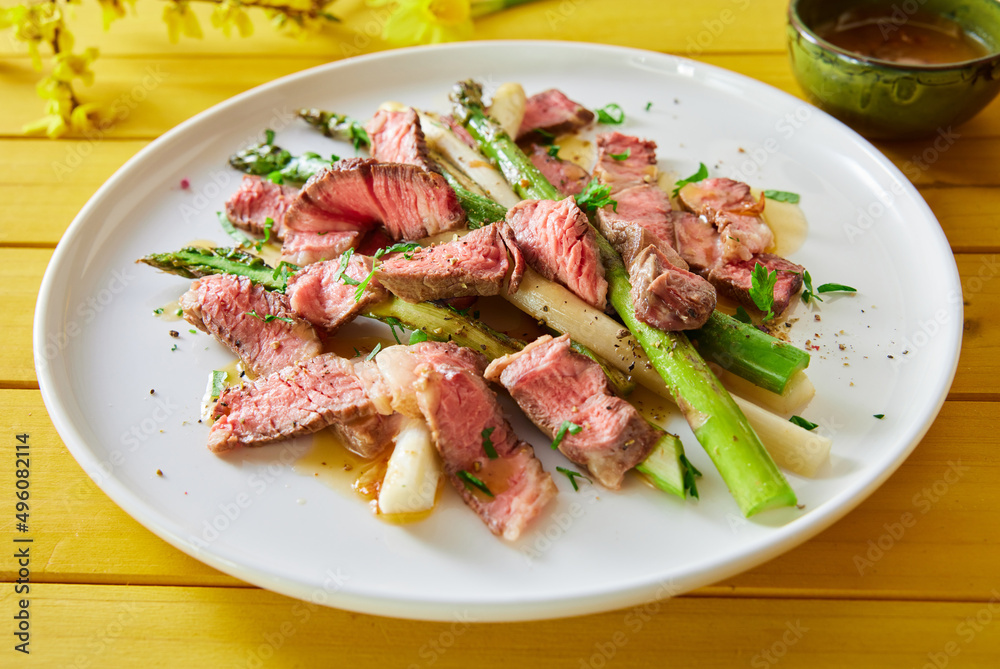 Appetizing beef fillet with asparagus served on table