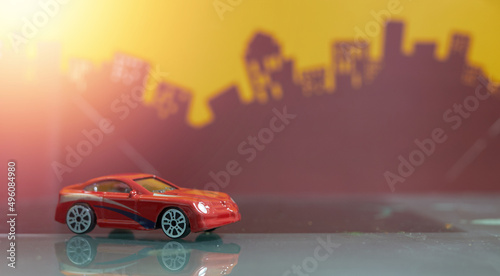 Fototapeta Naklejka Na Ścianę i Meble -  Red  Saloon car toy selective focus on blur city background