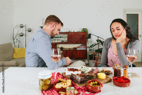 concept of phubbing in couple relationship - bored wife having aperitif with husband - distracted man snubbing woman - boring date photo