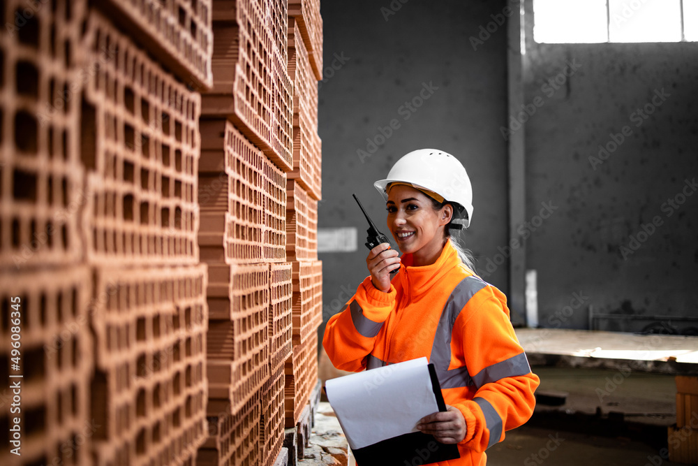Industrial production of clay bricks for building industry and female worker checking inventory via radio in factory. Industrial production of clay bricks for building industry and female worker checking inventory via radio in factory.