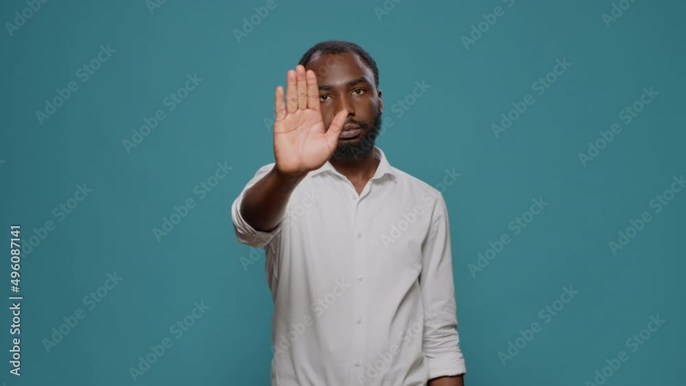 Negative person doing stop symbol with palm in studio, expressing denial and rejection. Young man denying and disapproving with idea, raising hand to dismiss and decline suggestion. Negative person doing stop symbol with palm in studio, expressing denial and rejection. Young man denying and disapproving with idea, raising hand to dismiss and decline suggestion.
