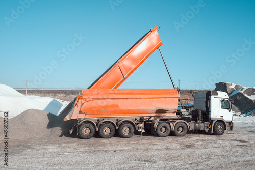 trucks carry and unload crushed stone at an asphalt concrete plant, which is needed for road construction