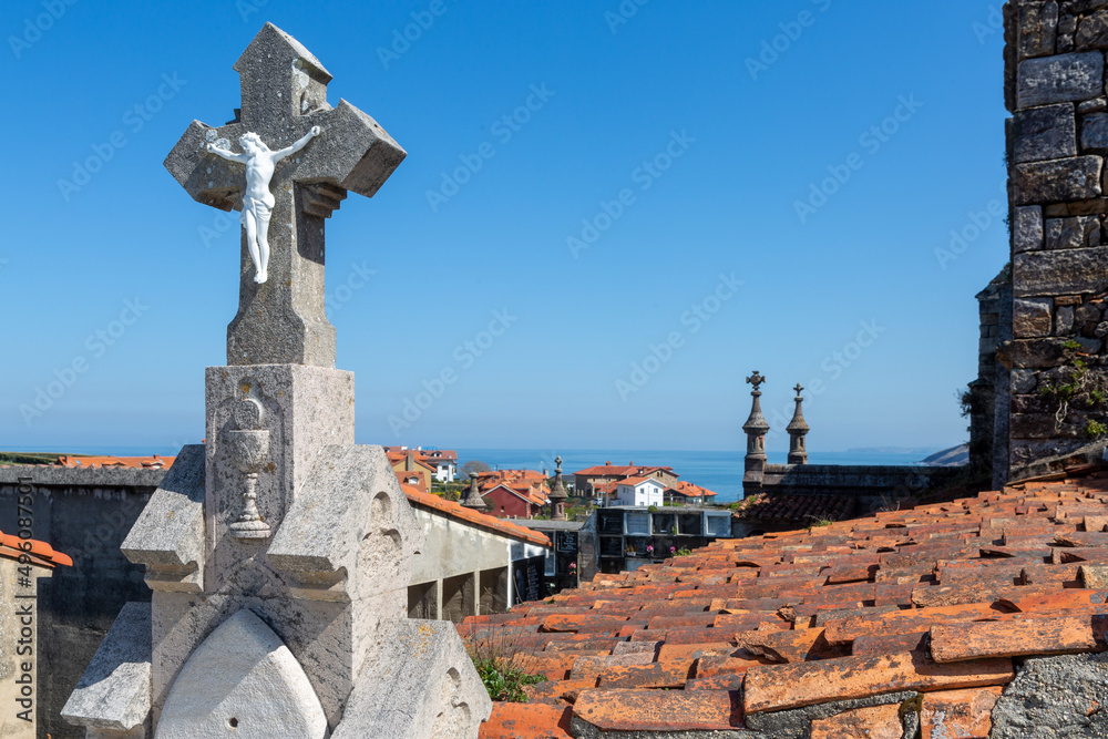 Stone cross with figure of jesus christ in cemetery with sea view Stone cross with figure of jesus christ in cemetery with sea view