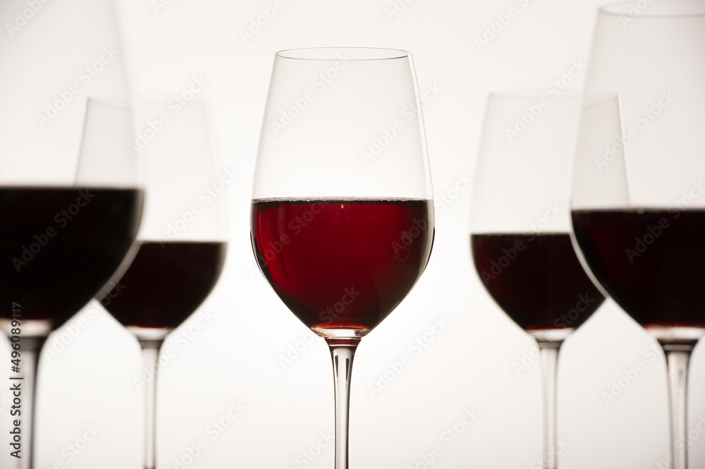Glasses with red grape wine and a bottle on a white glossy surface. High quality photo Glasses with red grape wine and a bottle on a white glossy surface. High quality photo