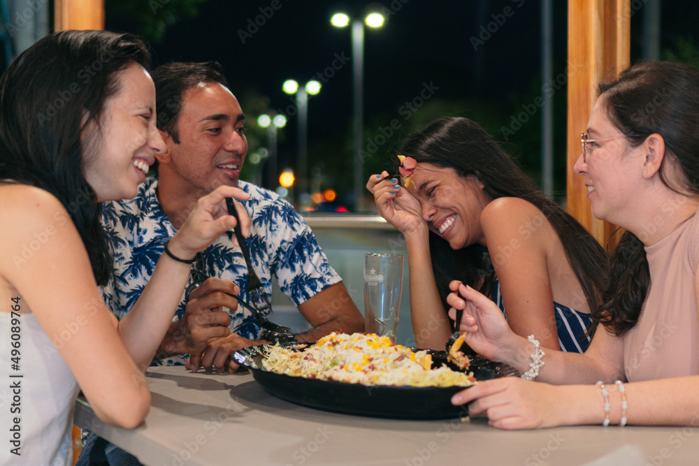 Group of friends eating fast food in a restaurant. Cheerful young people eating and enjoying themselves in a fast food restaurant.
