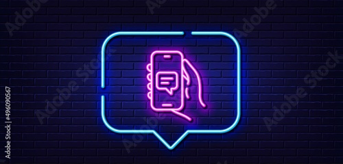 Neon light speech bubble. Chat app line icon. Hand hold phone sign. Cellphone with screen notification symbol. Neon light background. Chat app glow line. Brick wall banner. Vector