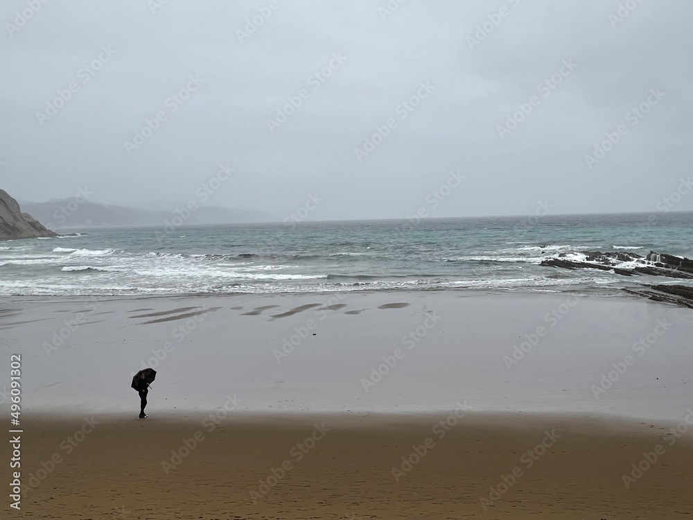 Mujer mirando el mar bajo la lluvia