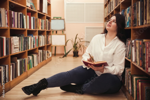 Plus size elegant woman in white shirt in  library