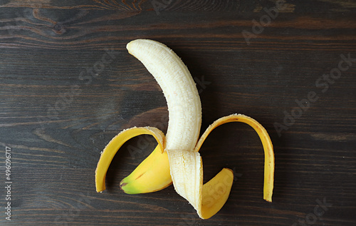 A finger of peeled fresh ripe banana isolated on black wooden backdrop
