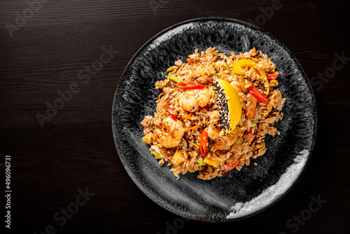 Fried rice with shrimp and vegetables in plate on wooden table background