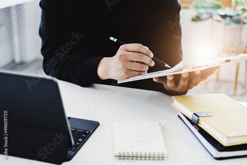 An accountant, businessman, auditor, economist man holding a pen pointing to a budget document and using tablet to examine and assess financial and investment risks for a company. photo