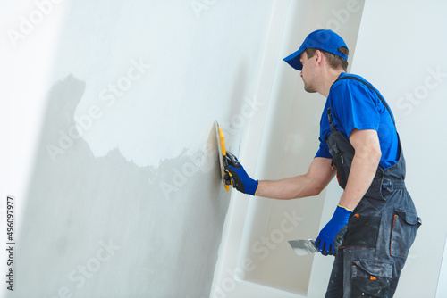 Tableau sur toile refurbishment. Plasterer worker spackling a wall with putty