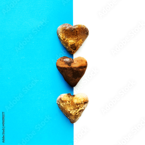 Three chocolate honey hearts on blue and white background,flat lay photo