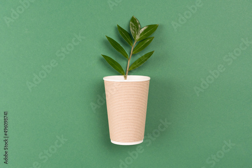Kraft paper coffee cup - biodegradable, compostable paper utensils for hot beverages. Paper cup on green background with copy space. Environmental conservation concept, selective focus photo