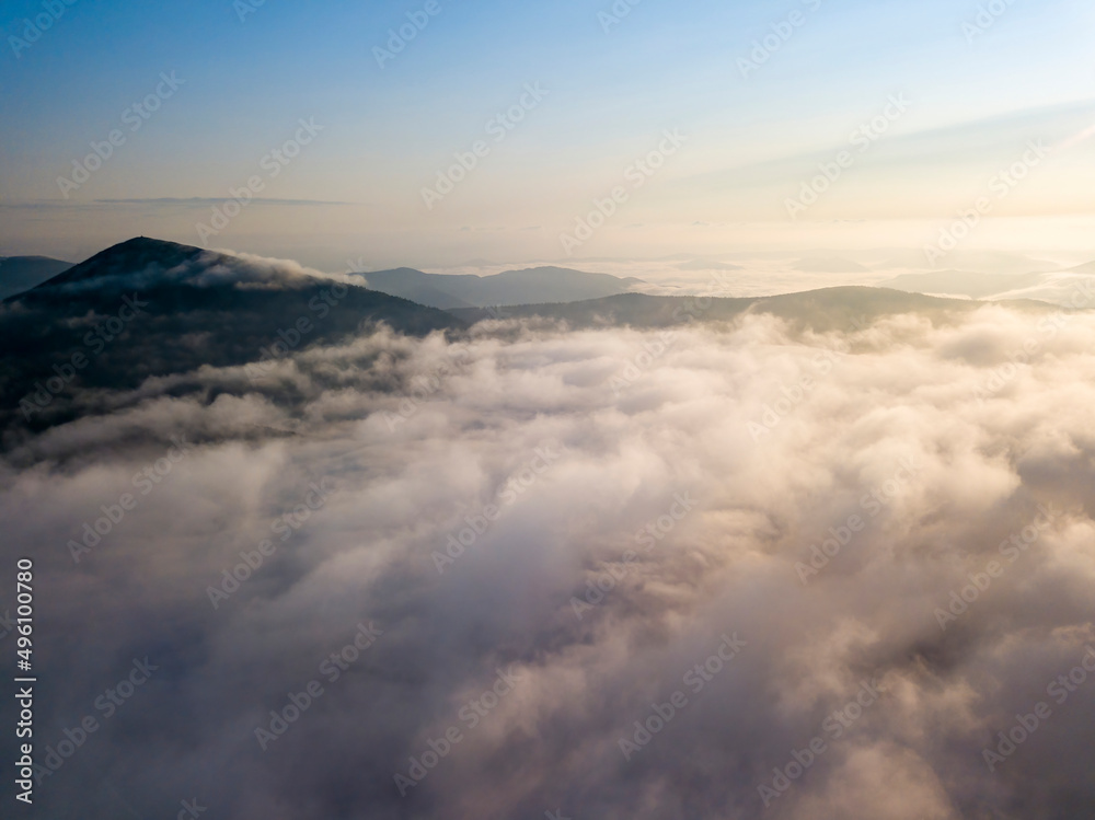 Flight over fog in Ukrainian Carpathians in summer. Mountains on the horizon. Aerial drone view.