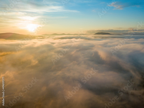 The rays of dawn over the fog in the Ukrainian Carpathians. Aerial drone view.