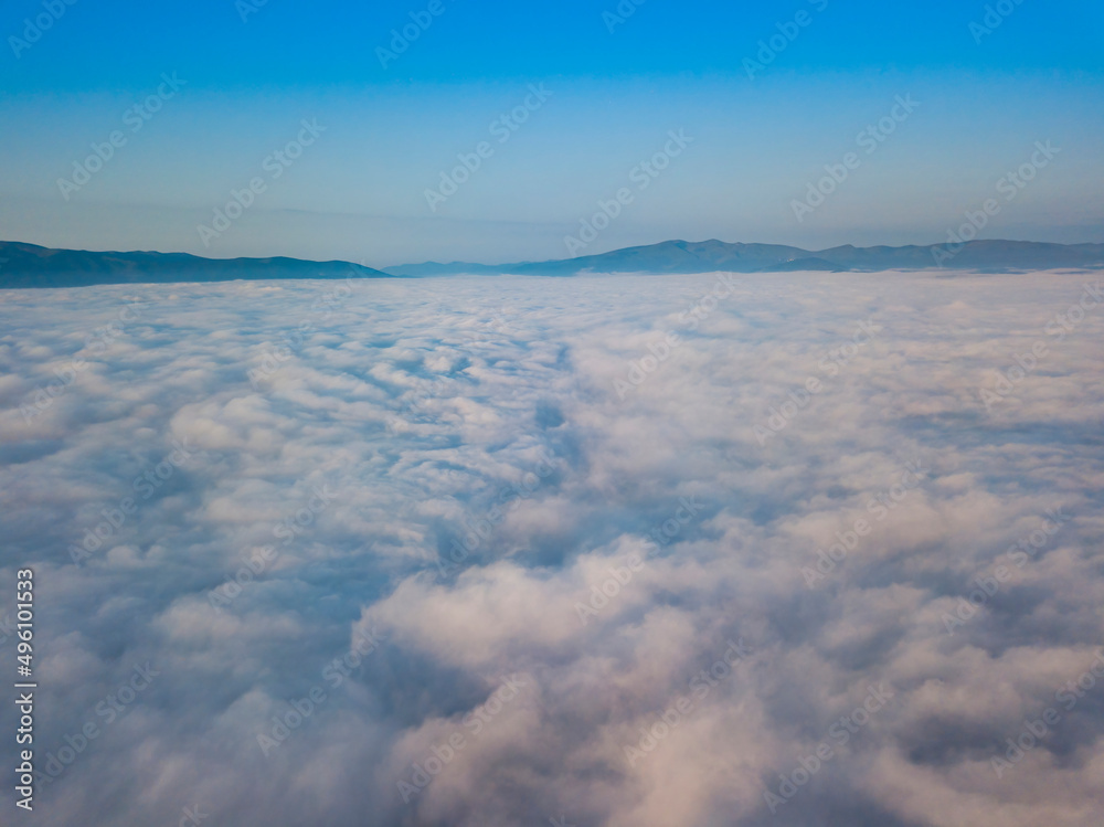Flight over fog in Ukrainian Carpathians in summer. Mountains on the horizon. Aerial drone view.