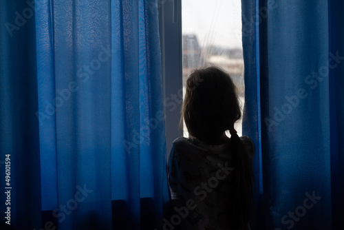 Little sad girl near window. Abuse of children concept