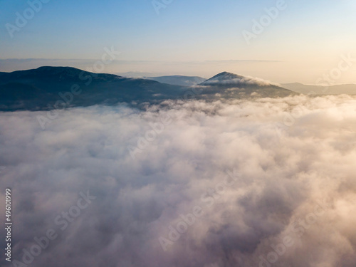 Flight over fog in Ukrainian Carpathians in summer. Mountains on the horizon. Aerial drone view.