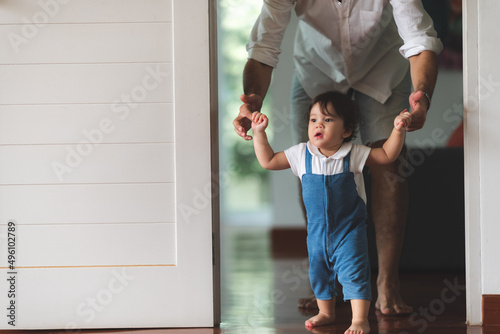 Fototapeta Naklejka Na Ścianę i Meble -  cute toddler little child family concept, baby learning to walk with father and mother to help care and holding hand, first step with childhood parent support, small love portrait little boy at home