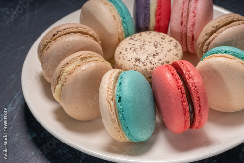 Colorful macarons in white plate on wooden table, Sweet makaron from almond flour and cream.