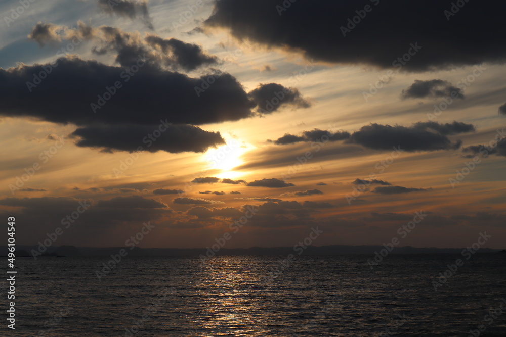 雲の合間から海に沈みゆく夕日