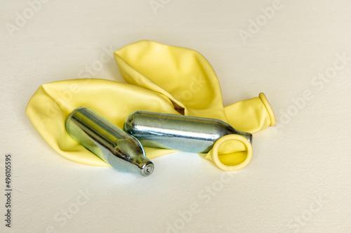 Pair of Nitrous oxide or laughing gas canisters and two balloons used for sniffing by addicts isolated photo