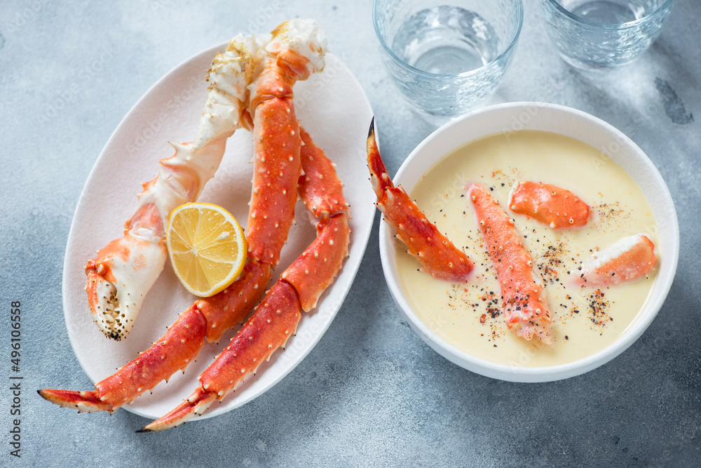 Corn cream-soup served with boiled kamchatka crab legs, horizontal shot on a light-blue stone background, selective focus Corn cream-soup served with boiled kamchatka crab legs, horizontal shot on a light-blue stone background, selective focus