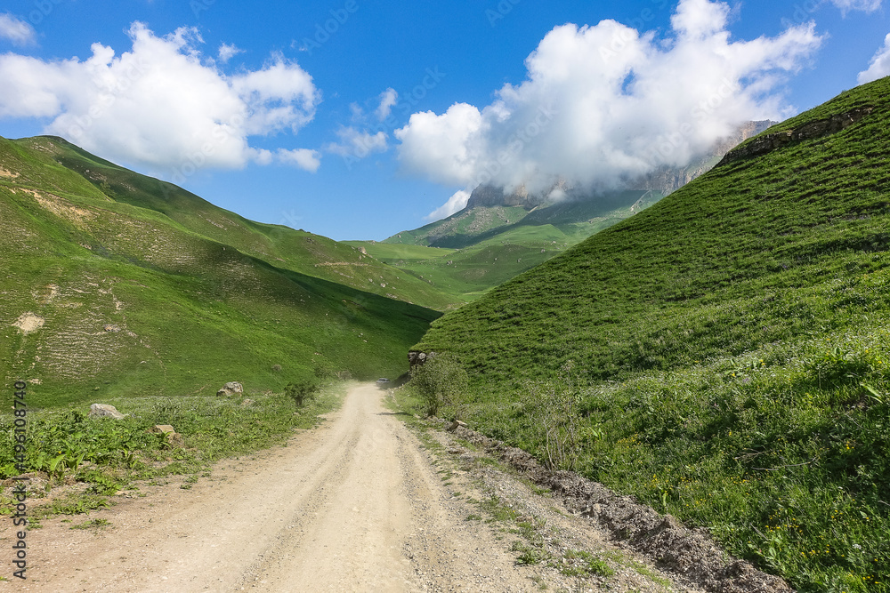 The landscape of the green Aktoprak pass in the Caucasus, the road and the mountains under gray clouds. Kabardino-Balkaria, Russia