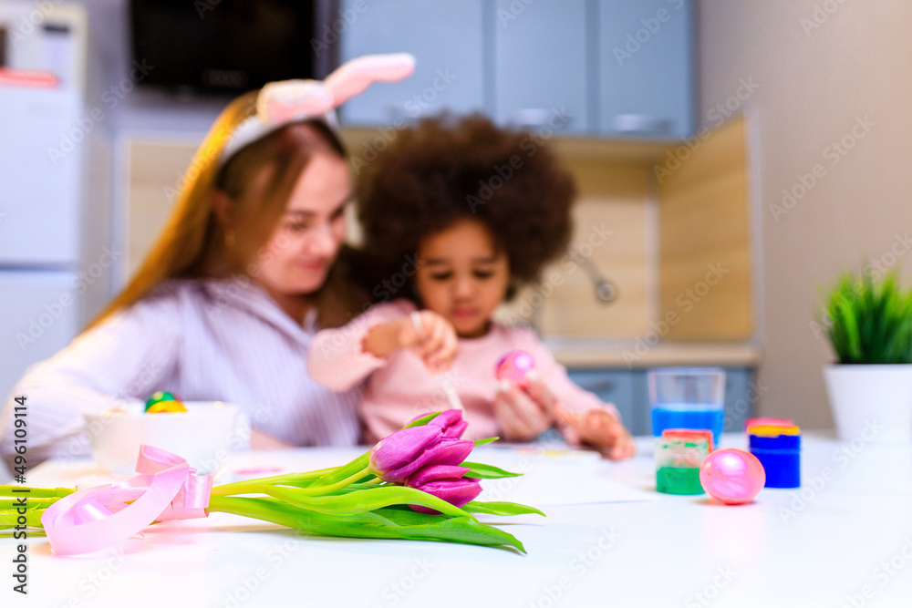 Fototapeta premium multiethnic family preparing to easter event at kitchen painting eggs