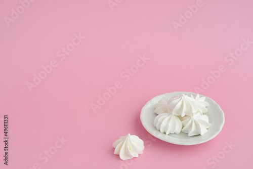 Vanilla homemade meringues a plate on pink table background, copy space. White marshmallows a plate