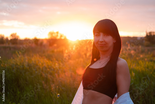 brunette woman in white blouse with baldric on summer field on sunset. peaceful time. millennial generation. calm female photo