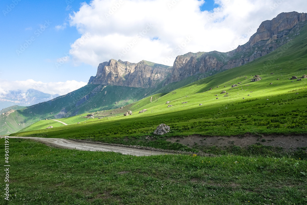 Fototapeta premium The landscape of the green Aktoprak pass in the Caucasus, the road and the mountains under gray clouds. Kabardino-Balkaria, Russia