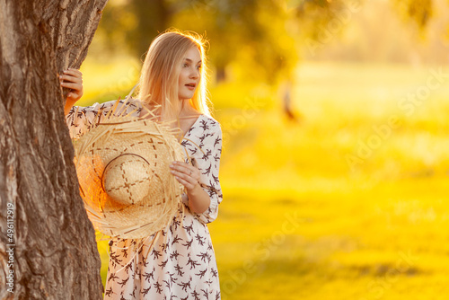 Beautiful delicate blonde with a straw hat and a summer dress in nature. Light fresh makeup in pink tones. Spring and summer beauty. Fashion.