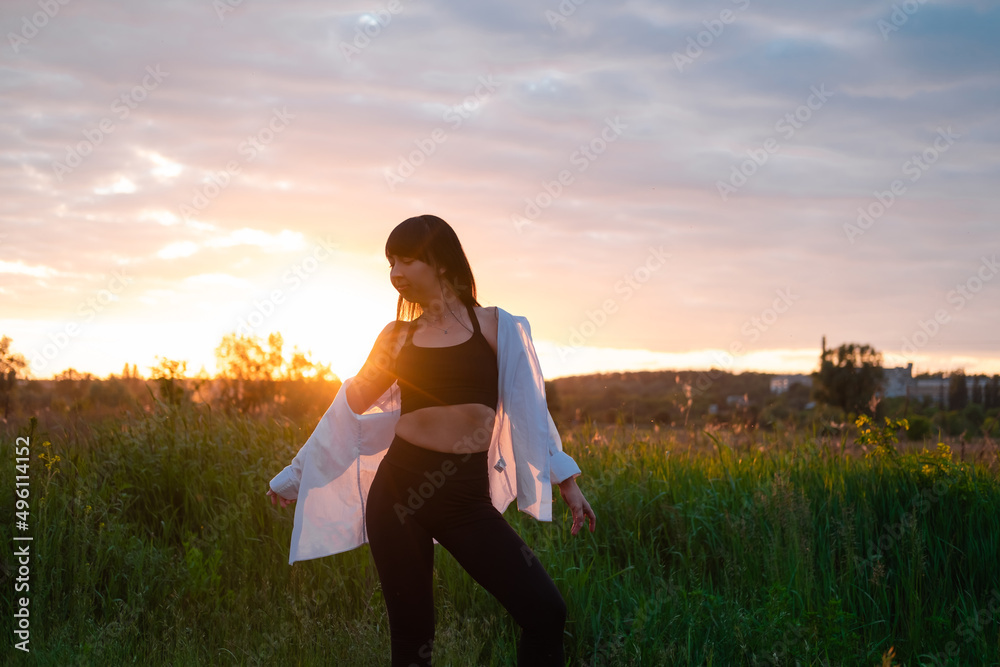 pretty young woman in white blouse on summer green field on sunset. happy peaceful time. millennial generation pretty young woman in white blouse on summer green field on sunset. happy peaceful time. millennial generation