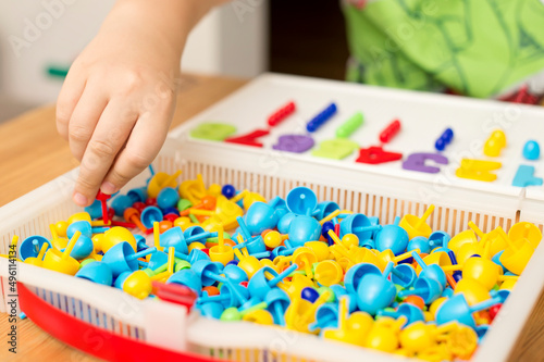 By provided numbers boy inserting pins. Play at home. Implement for children to develop fine motoric skills, logical thinking through play. Learn counting and stimulate imagination, creativity.