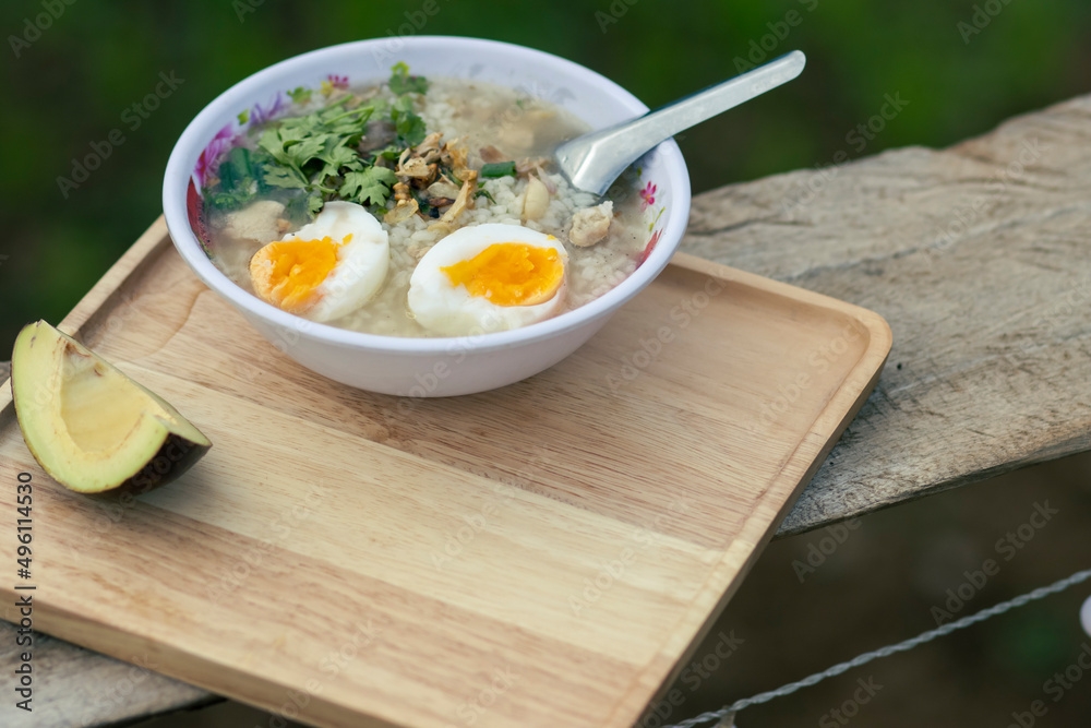 Porridge in a serving bowl with avocado on a wooden tray looks beautiful. Breakfast at a hill tribe house in Thailand Porridge in a serving bowl with avocado on a wooden tray looks beautiful. Breakfast at a hill tribe house in Thailand