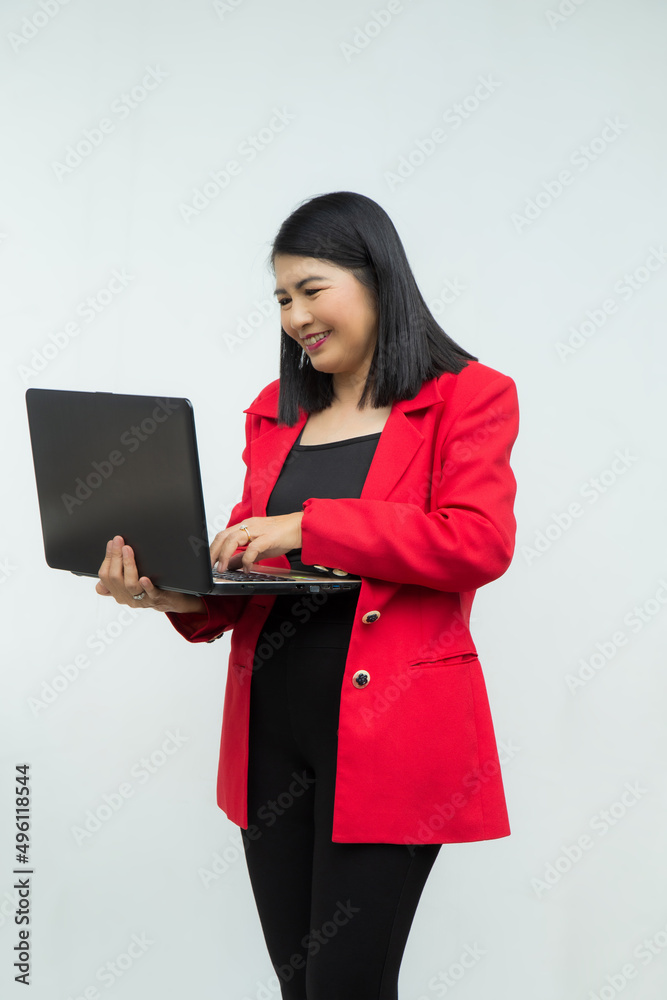 Portrait confident middle-aged Asian woman wearing red jacket using a laptop isolated on white background. Portrait confident middle-aged Asian woman wearing red jacket using a laptop isolated on white background.