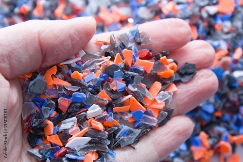 A pile of microplastics - small pieces of hard plastic on palm, intended for further processing.