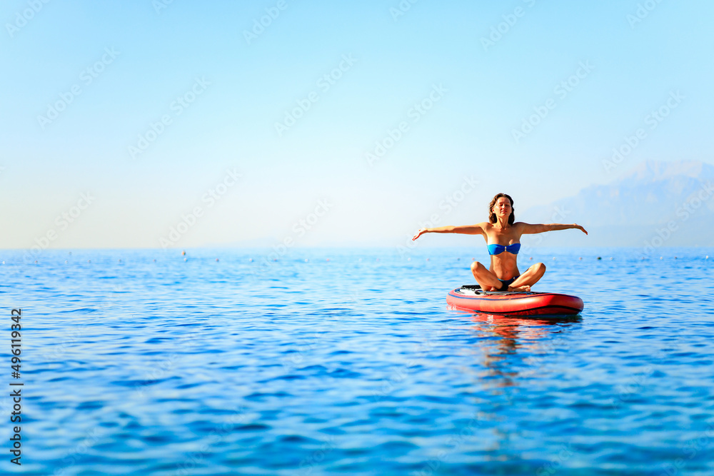 Woman sitting on sup board and enjoying peace and quiet outdoors Woman sitting on sup board and enjoying peace and quiet outdoors