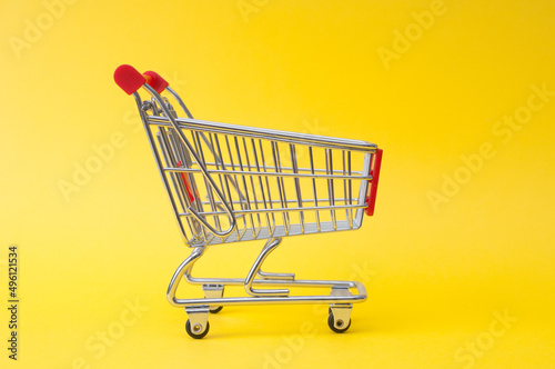 Empty trolley shopping on a yellow background