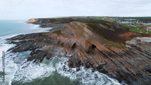 AERIAL: Wide circle of set of three caves and rocky coastline, Port Eynon, Gower, 4k Drone photo