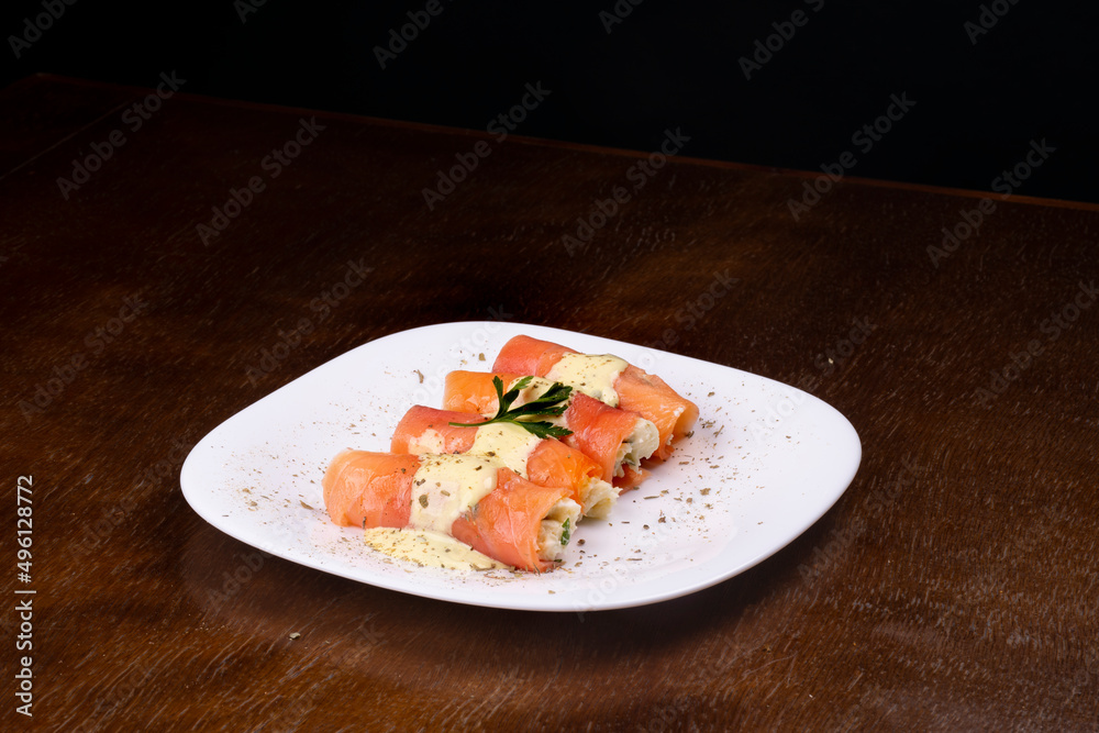 plate of rolled salmon stuffed with cream cheese and parsley angle view on wooden table
