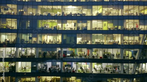 Aerial view of office windows in modern skyscrapers at night.