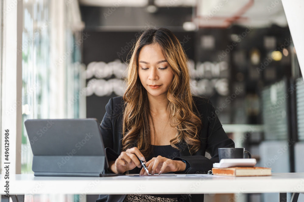 Concentrated Asian business woman working on her computer tablet. Start-up office background. Concentrated Asian business woman working on her computer tablet. Start-up office background.