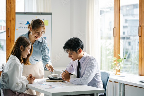 Young Asian businesswoman giving presentation to colleagues in board room.