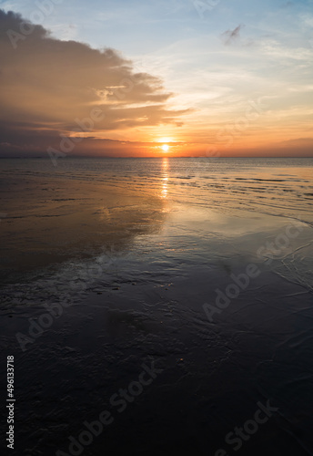 Sunset sky vertical over sea in the evening and reflection on the beach